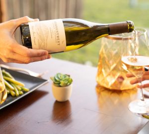 a person pouring a bottle of chardonay