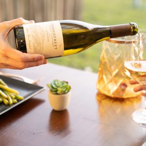 a person pouring a bottle of chardonay
