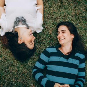 a couple of women laying on the grass