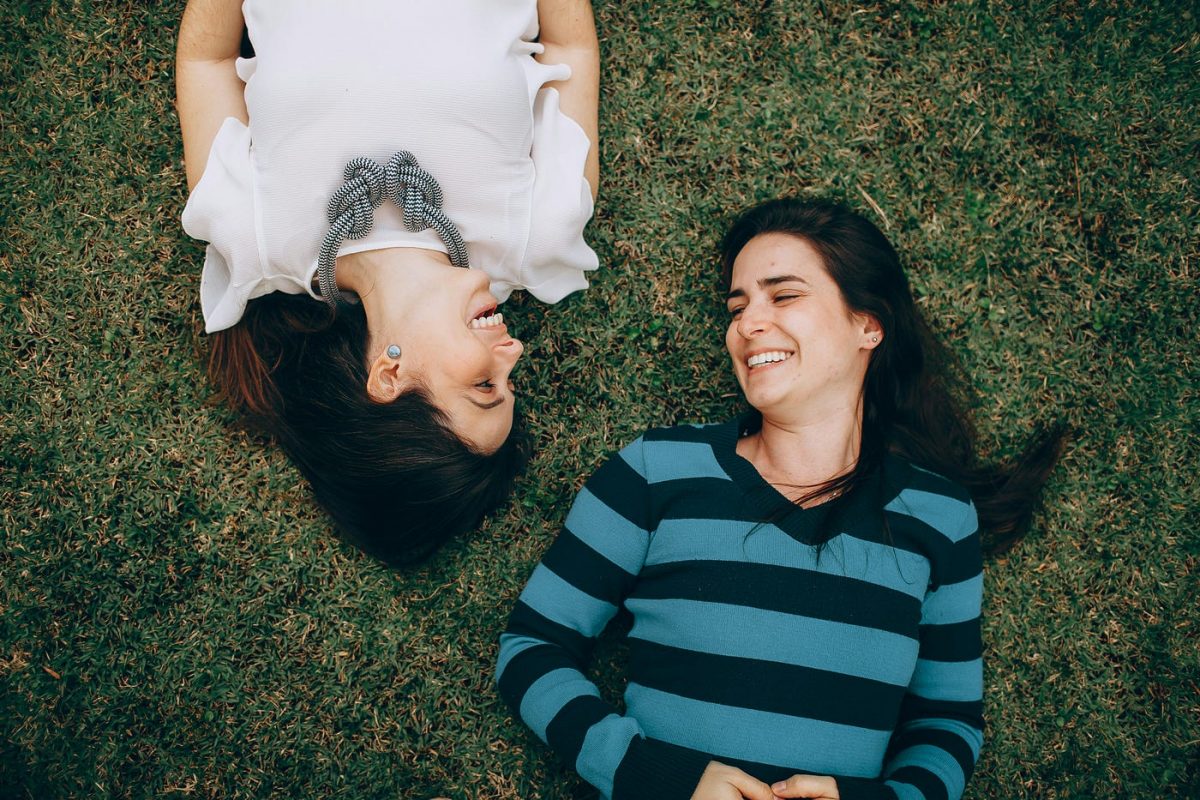 a couple of women laying on the grass