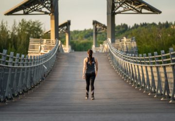a woman walking along a bridge in edmonton