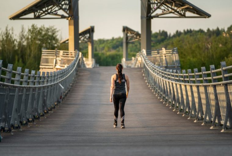 a woman walking along a bridge in edmonton