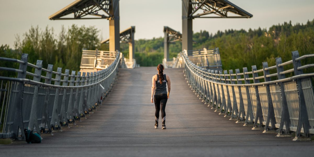 a woman walking along a bridge in edmonton