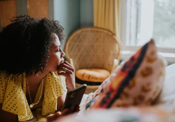 a woman on a device looking out a window