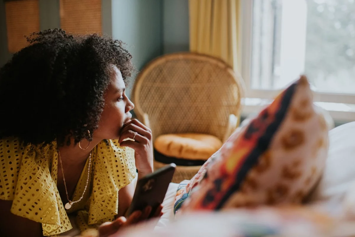 a woman on a device looking out a window