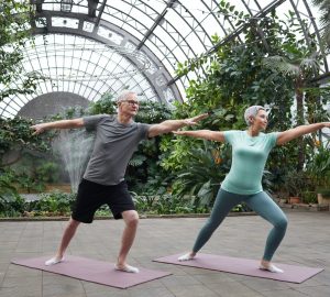 a couple doing yoga in a greenhouse