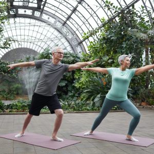 a couple doing yoga in a greenhouse