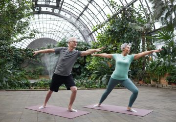 a couple doing yoga in a greenhouse
