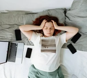 a woman laying on bed holding her head