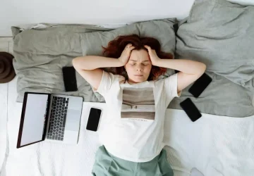 a woman laying on bed holding her head