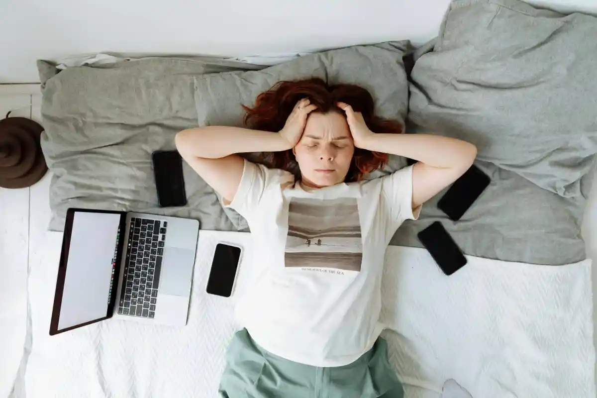 a woman laying on bed holding her head