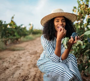 a woman tasting grapes at a vineyard