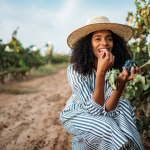 a woman tasting grapes at a vineyard