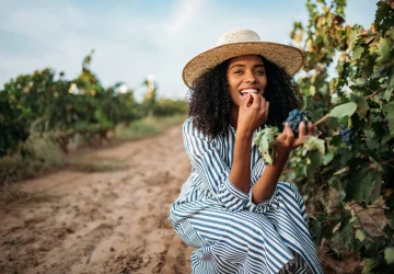 a woman tasting grapes at a vineyard