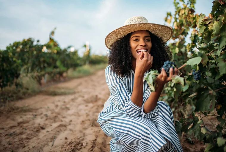 a woman tasting grapes at a vineyard