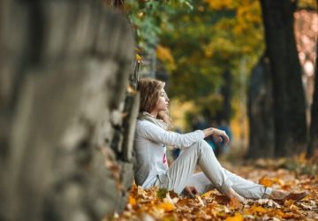 a woman sitting outside in the fall under a tree
