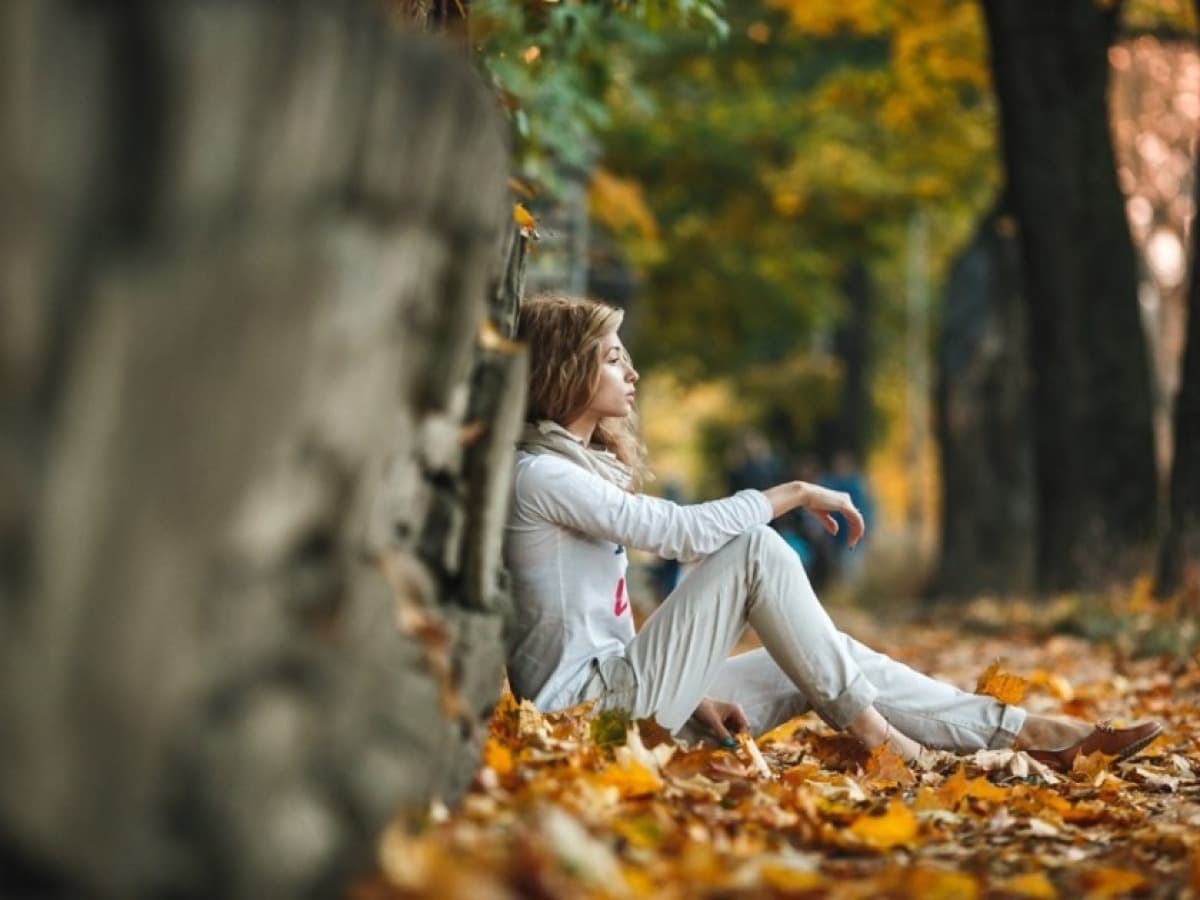 a woman sitting outside in the fall under a tree